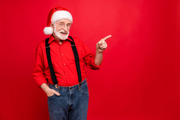 Portrait of his he nice confident cheerful cheery content glad bearded Santa pointing forefinger aside ad like copy space isolated over bright vivid shine vibrant red background - Foto, Imagem