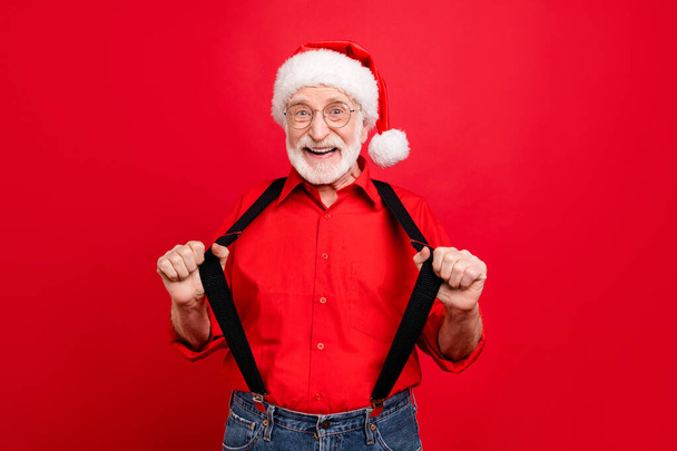 Portrait of his he nice trendy cheerful cheery glad excited bearded Santa Claus pulling suspenders isolated over bright vivid shine vibrant red background - Photo, Image