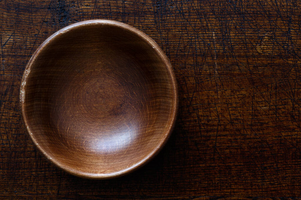 Empty dark wooden bowl isolated on dark brown wood from above. - Foto, Imagem