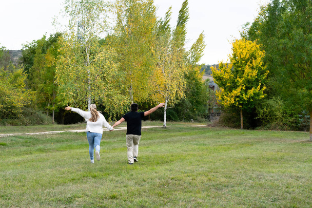 Pareja agarrados de la mano corren por el parque felices  - Foto, Bild