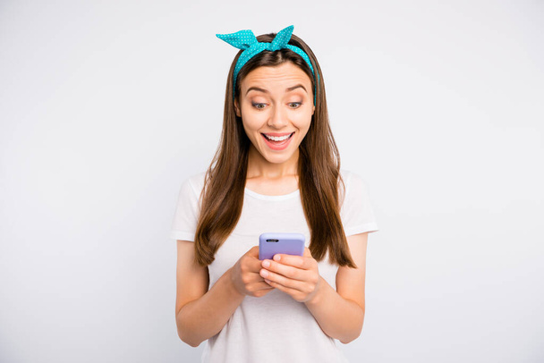 Portrait of astonished cheerful girl using her smartphone get notification from social network account wear casual style outfit isolated over white color background - 写真・画像