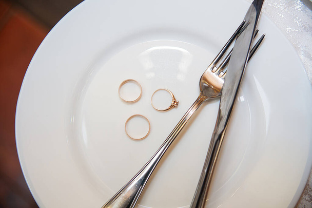 Geschirr, ein schöner goldener Ehering auf einem weißen Teller - Foto, Bild