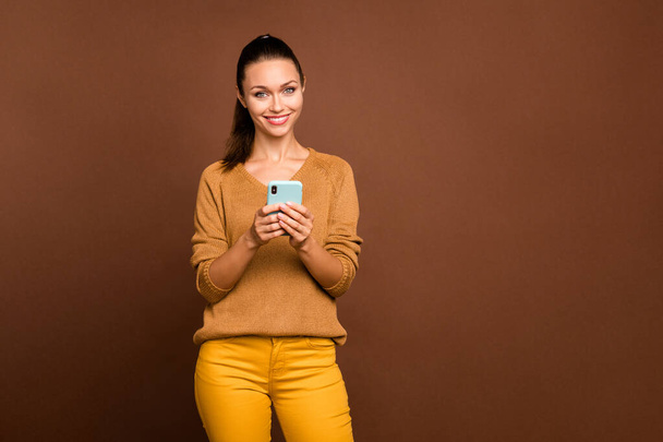 Photo of cheerful positive cute nice sweet pretty charming girl blogger sharing her opinion via telephone held with hands smiling toothily isolated over brown pastel color background - Fotó, kép