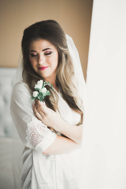 Luxus menyasszony fehér ruhában pózol, miközben készül az esküvői szertartás - Fotó, kép