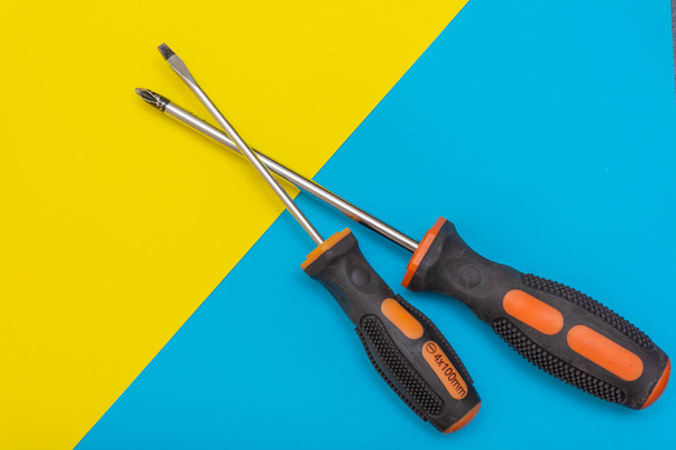 Home improvement: two screwdrivers (philips and slotted) on a blue and yellow flat lay background with copy space. - Photo, Image