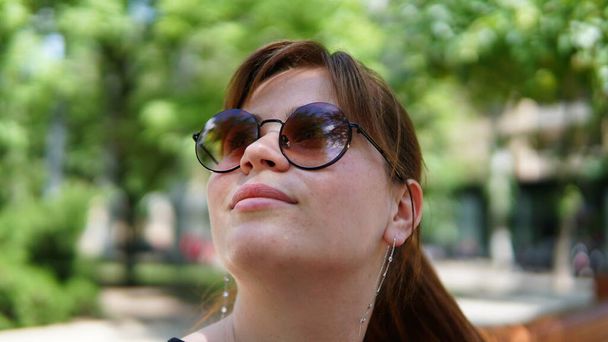Mulher jovem impressionante olhando para cima com reflexão legal em seus óculos de sol
 - Foto, Imagem