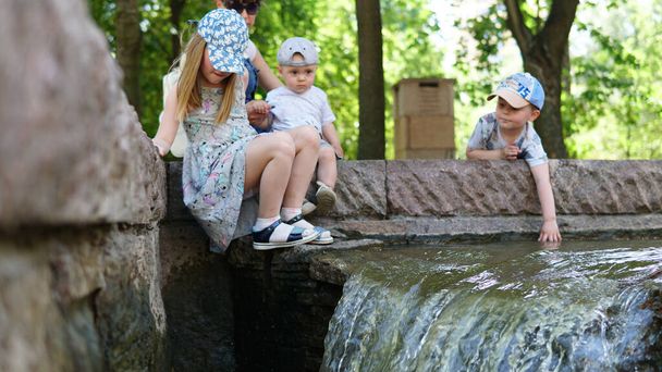 Счастливая семья, маленькие мальчики с матерью у фонтана
 - Фото, изображение