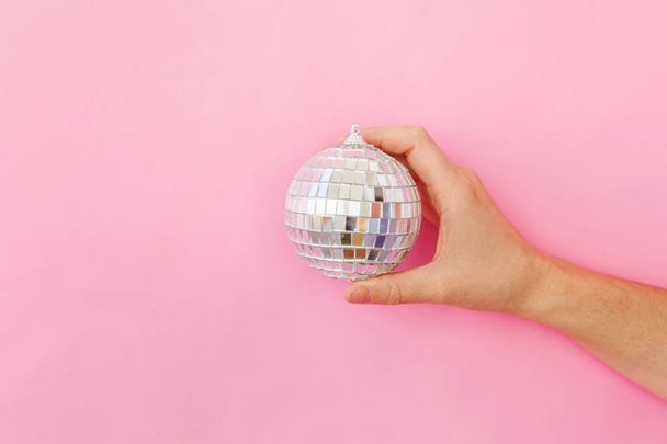 Simply minimal design female woman hand holding Christmas ornament disco ball isolated on pink pastel colorful trendy background - Foto, Imagem