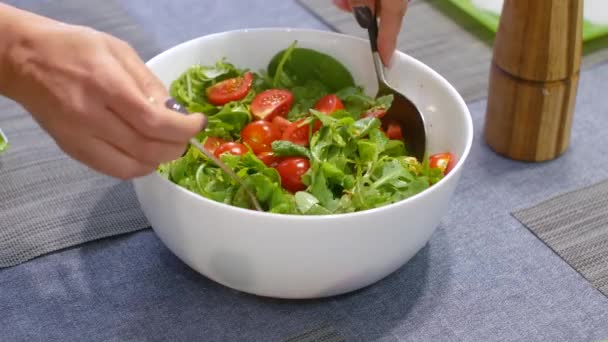 Woman mixing delicious superfood salad ingredients with spoons in kitchen - Footage, Video