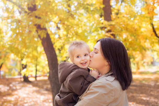 Familie im Herbstpark zwischen gelben Blättern. Eine junge Mutter mit einer kleinen Tochter spielt im Herbstpark mit Blättern. Herbststimmung - Foto, Bild
