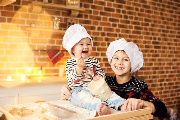Les enfants sont cuits et joués avec de la farine et de la pâte dans la cuisine
 - Photo, image