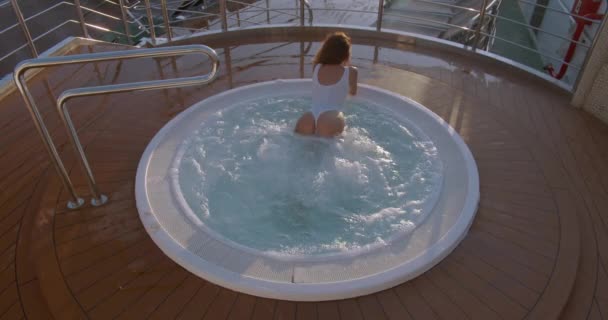 Женщина расслабляется в гидромассажной ванне джакузи на открытом воздухе на роскошном курорте
 . - Кадры, видео