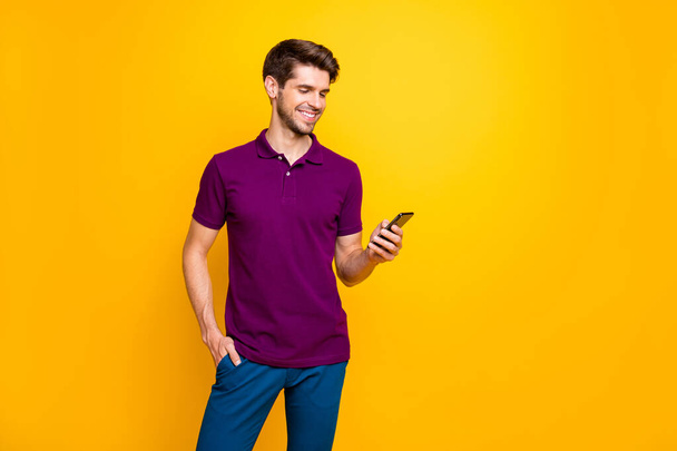 Portrait of his he nice attractive content cheerful cheery glad guy wearing violet shirt using gadget sharing repost smm like isolated on bright vivid shine vibrant yellow color background - Foto, immagini
