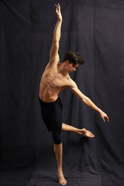 Young ballet dancer in motion on black fabric background - 写真・画像