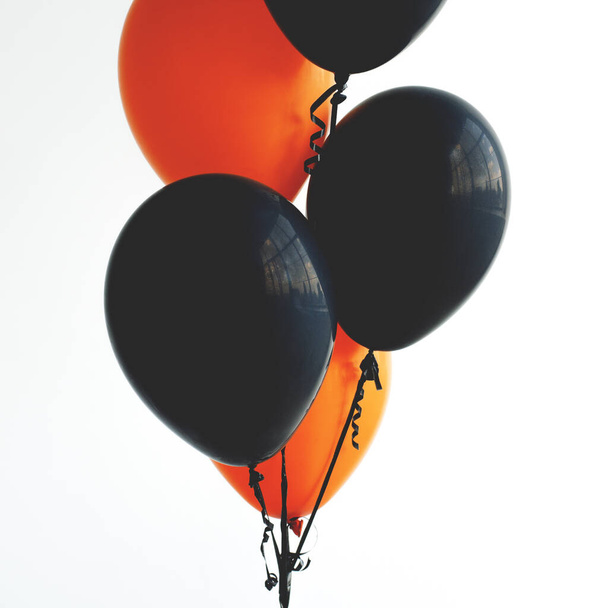 A bunch of helium balloons in orange and black.  - 写真・画像