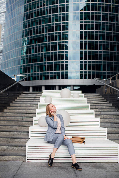 young happy business woman talking on the phone in the background of an office building - Foto, Imagem