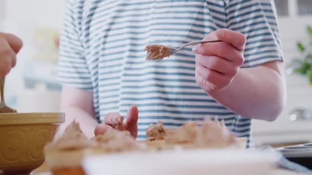 Young Downs syndrom pár pečení v kuchyni doma zdobení cupcakes s polevou - výstřel ve zpomaleném filmu - Záběry, video