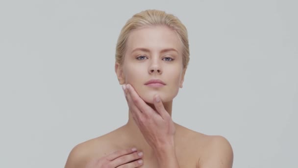 Studio portrait of young, beautiful and natural blond woman applying skin care cream. Face lifting, cosmetics and make-up. - Séquence, vidéo