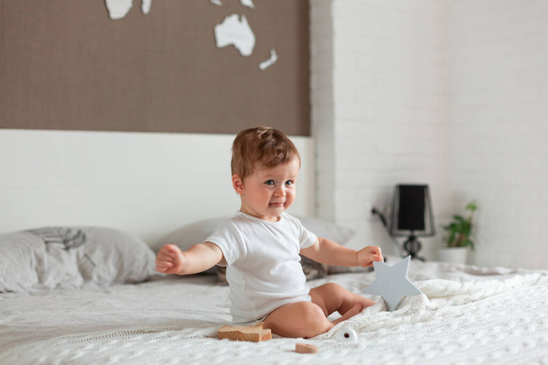 Happy baby sitting on a big bed - Фото, изображение