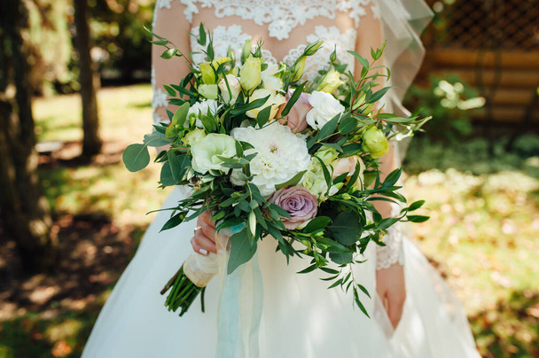Beautiful bride is holding a wedding colorful bouquet. - Foto, Imagen
