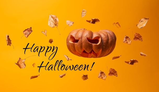 Zucca spaventosa, foglie secche volanti e iscrizione Happy Halloween
 - Foto, immagini