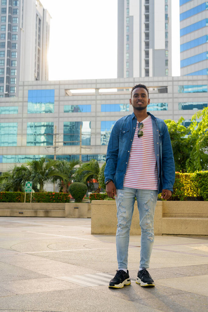 Full body shot of happy young African man smiling in the city outdoors - Foto, imagen