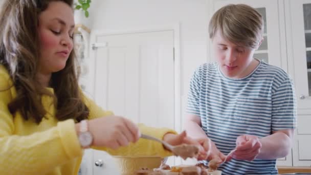 Young Downs Syndrome couple baking in kitchen at home decorating cupcakes with icing - shot in slow motion - Filmati, video