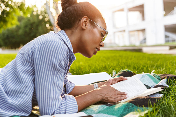 Image of attractive african american woman reading book in park - Фото, зображення
