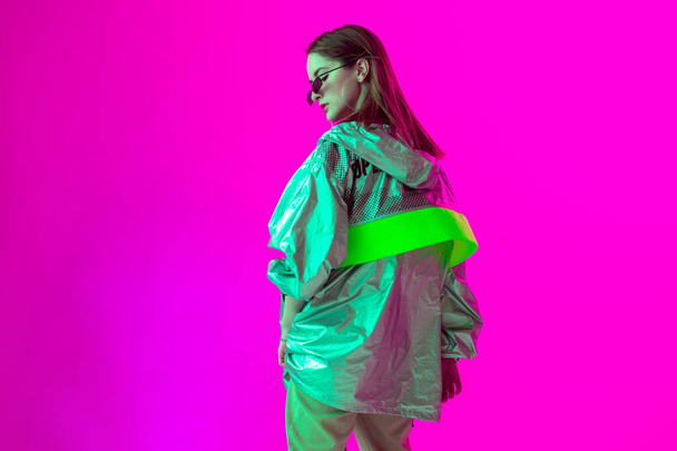 Young stylish girl dancing in the Studio on a colored neon background. Music poster design. - Foto, Imagen