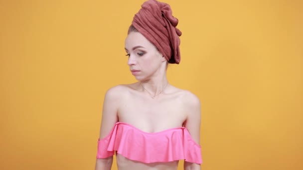 Młoda dziewczyna z ręcznikiem na głowie na białym tle pomarańczowe pokazuje emocje - Materiał filmowy, wideo