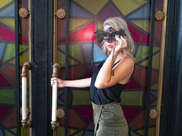 Blonde girl in a black masquerade mask. - Foto, Bild
