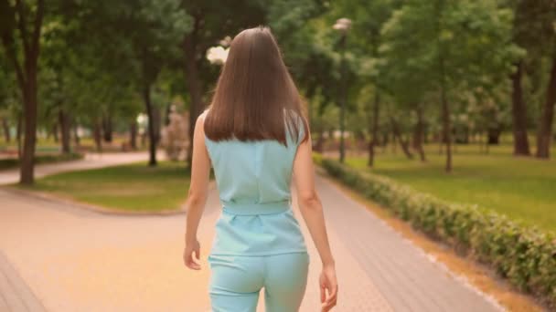 takaisin näkymä lähikuva nainen kävelee kadulla kaupungin puistossa kesällä ulkona
 - Materiaali, video