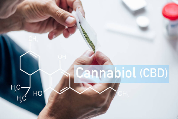 cropped view of man holding blunt of medical cannabis with cbd molecule illustration - 写真・画像
