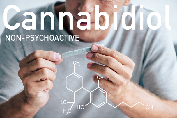 обрезанный вид улыбающегося взрослого мужчины, скатывающегося тупым с медицинской марихуаной рядом с непсихоактивной иллюстрацией CBD
 - Фото, изображение