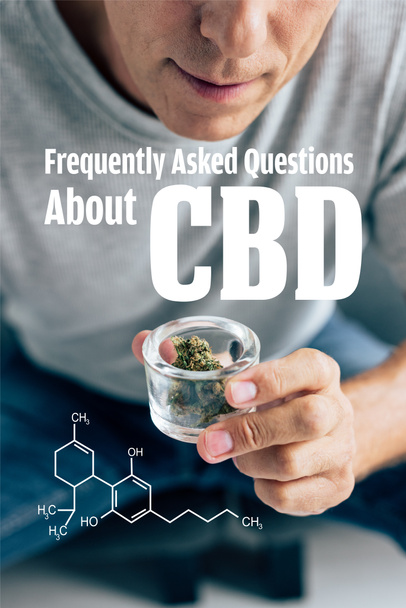 cropped view of man in t-shirt looking at medical cannabis in glass container with frequently asked questions about cbd illustration - 写真・画像