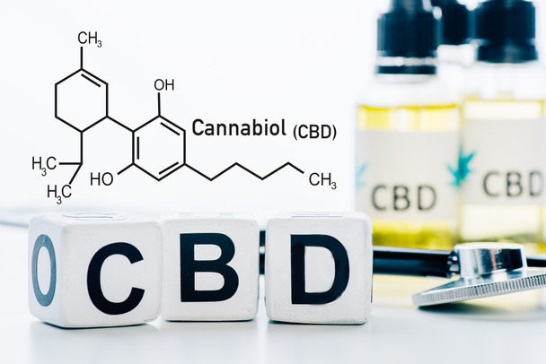 selective focus of cubes with cbd lettering near oil and stethoscope isolated on white with cbd molecule illustration - Photo, Image