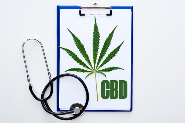 vista dall'alto della foglia di cannabis medica sugli appunti con scritte cbd vicino allo stetoscopio su sfondo bianco
 - Foto, immagini