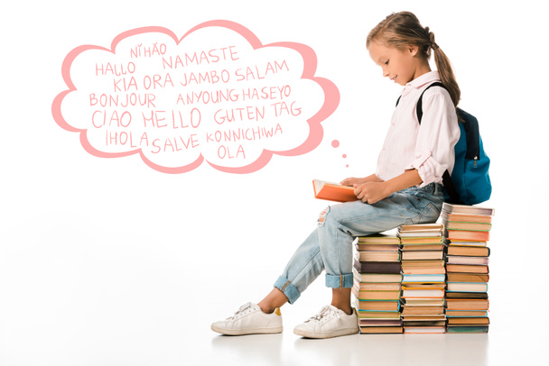 alegre colegial sentado en los libros y la lectura cerca de cartas de saludo en blanco
  - Foto, Imagen