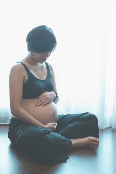 Nahaufnahme einer schwangeren Frau mit ihren Händen auf dem Bauch. - Foto, Bild