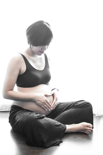Közelkép egy terhes nőről, akinek a keze a hasán van.. - Fotó, kép