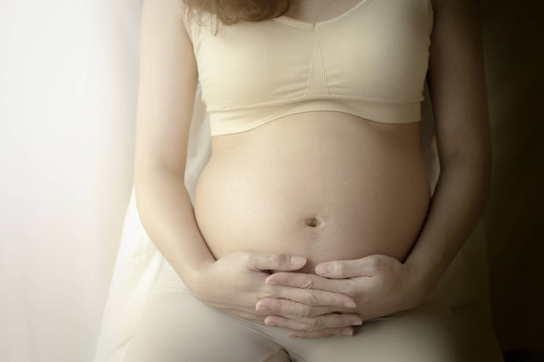 Acercamiento de la mujer embarazada con las manos en el vientre
. - Foto, imagen