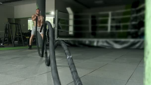 Fitness-urheilija käyttää taisteluköysiä koulutuksessa. Intensiivinen harjoitus. Super hidastettuna
 - Materiaali, video