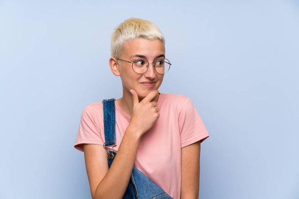 Teenager dívka s montérkami na modré zdi myšlení nápad - Fotografie, Obrázek