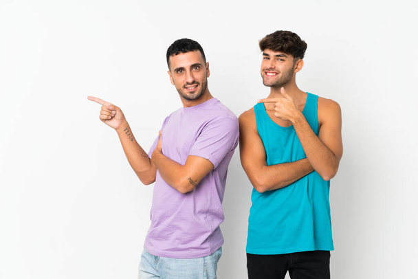 Δύο άνδρες πάνω από απομονωμένο φόντο δείχνοντας το δάχτυλο προς την πλευρά στην πλευρική θέση - Φωτογραφία, εικόνα