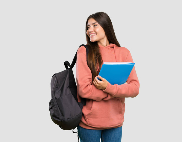Młoda studentka trzymająca zeszyty z skrzyżowanymi ramionami i szczęśliwa na szarym tle - Zdjęcie, obraz