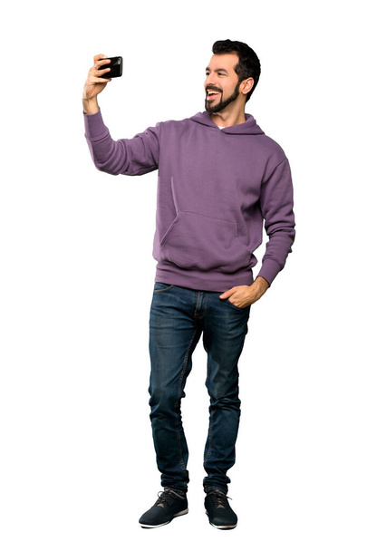 Full-length shot of Handsome man with sweatshirt making a selfie over isolated white background - Foto, afbeelding