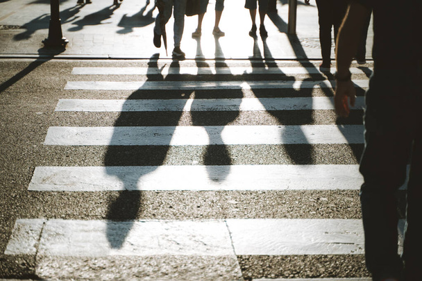 Pedestrian 'ın gölgesi güneşli bir öğleden sonra karşıdan karşıya geçiyor - Fotoğraf, Görsel