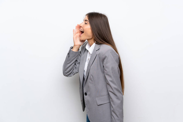 Young business woman over isolated white background shouting with mouth wide open to the lateral - Foto, immagini