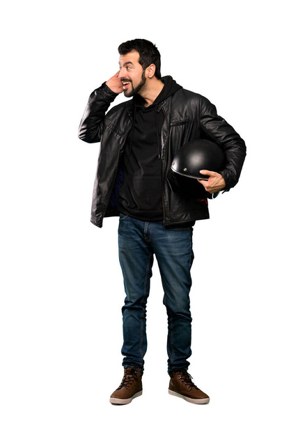 Полнометражный снимок человека-байкера, слушающего что-то, положив руку на ухо на изолированном белом фоне
 - Фото, изображение