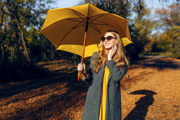 Girl, with yellow umbrella, in the Park with yellow leaves, autumn time - Fotó, kép